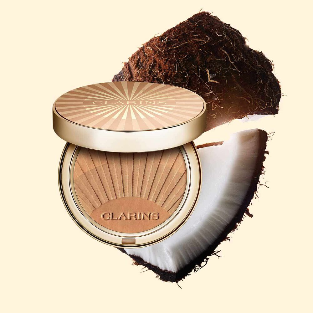 Packshot of Clarins bronzing powder positioned beside some coconut slide on a light orange background