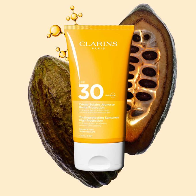 Photo of Clarins Youth-Protecting Sunscreen High Protection SPF 30 for the body, among collagen molecules and cocoa beans.