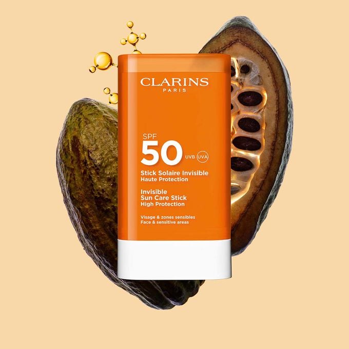 Packshot of Clarins Invisible Sun Care Stick High Protection SPF 50 for the face among collagen molecules and cocoa beans.