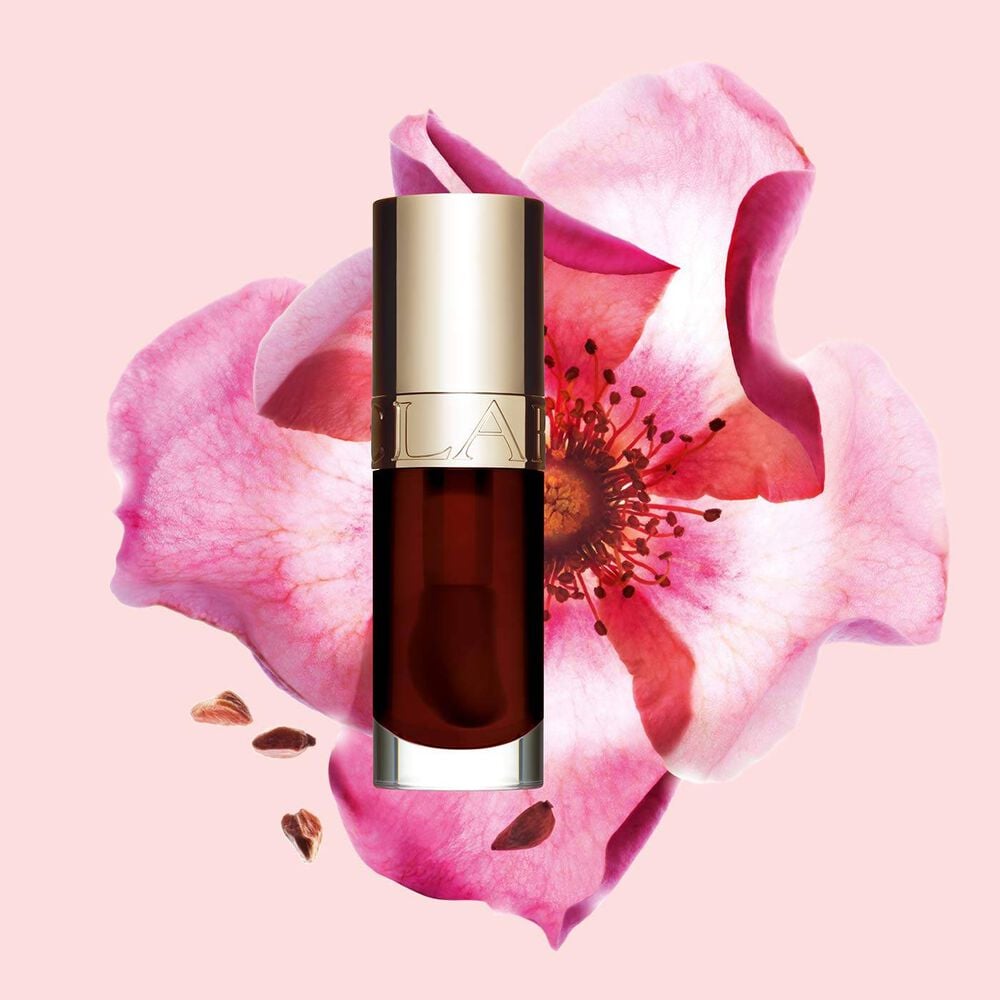 Packshot of Clarins Lip Comfort Oil Chocolate, placed next to a sweetbriar rose on a light pink background.