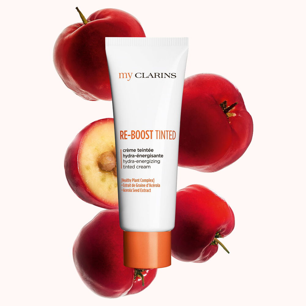 Packshot of a boosting and moisturizing tinted cream alongside acerola seeds on a light blue background.