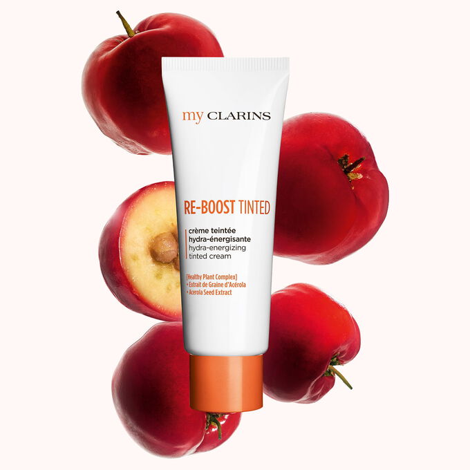 Packshot of a boosting and moisturizing tinted cream alongside acerola seeds on a light blue background.