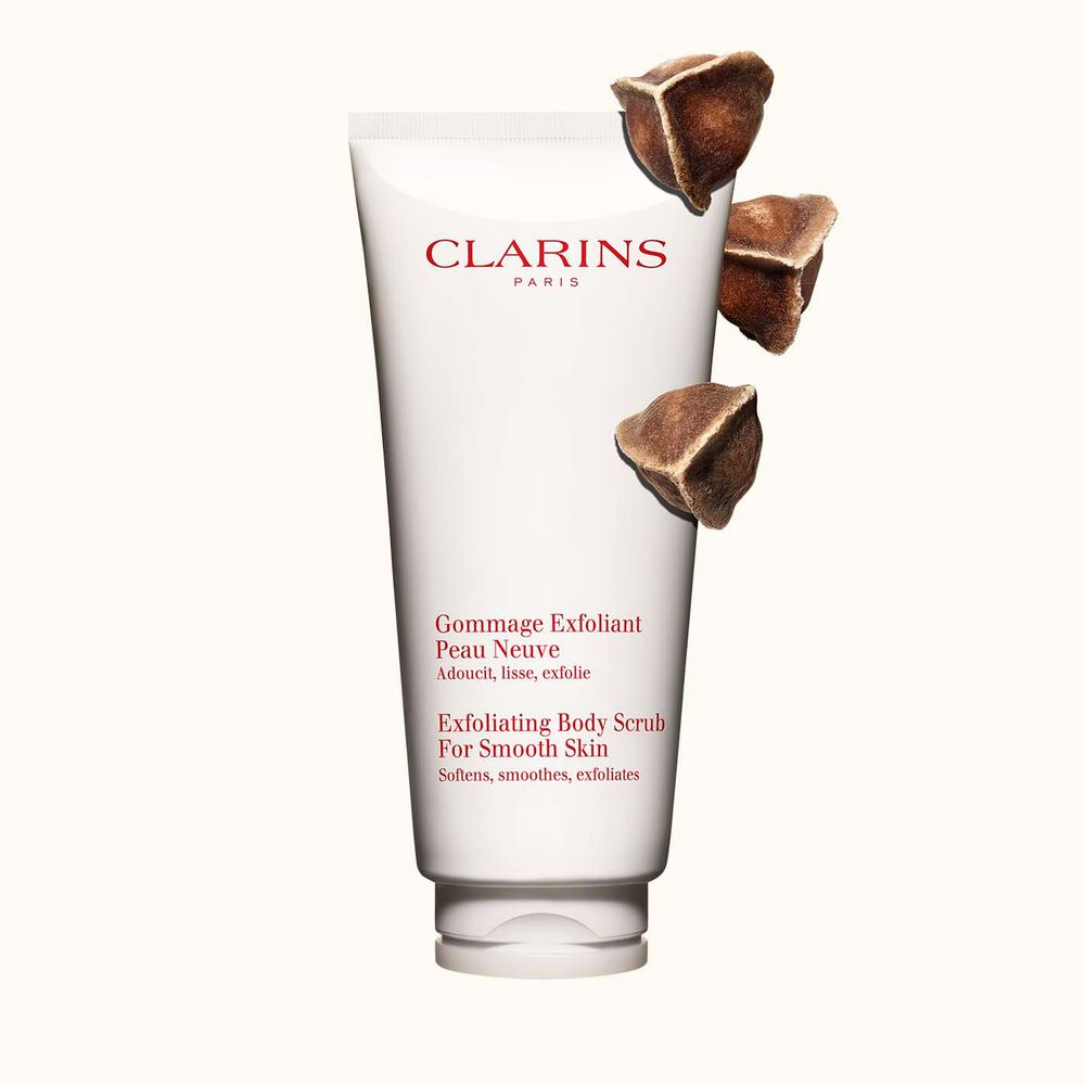 Packshot of Clarins Exfoliating Body Scrub for Smooth Skin placed next to moringa nuts on a light beige background