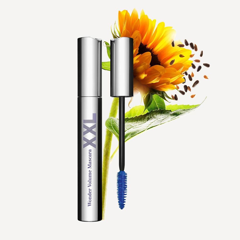 Packshot of Clarins Blue Volumizing Mascara Supra Volume XXL placed next to a sunflower on a light grey background