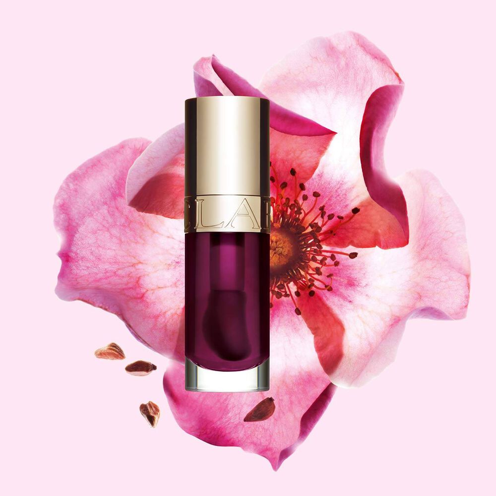 Packshot of Clarins Lip Comfort Oil Plum, placed next to a sweetbriar rose on a light pink background.