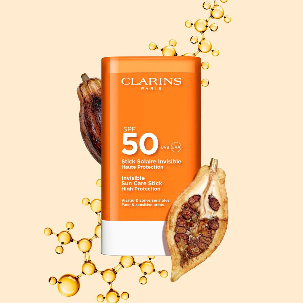 Packshot of Clarins Invisible Sun Care Stick High Protection SPF 50 for the face among collagen molecules and cocoa beans.