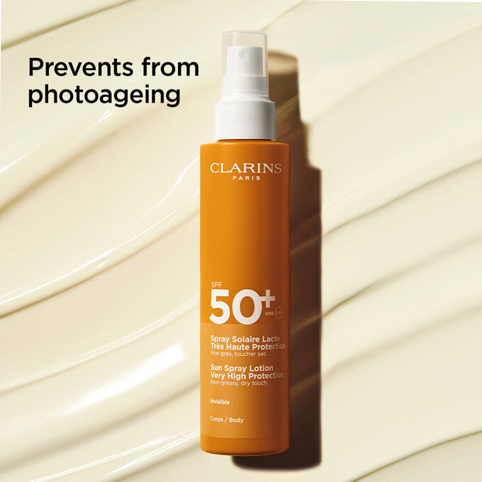 Packshot on textured background of body sun milk 50+ spray with text about its anti-photoageing action