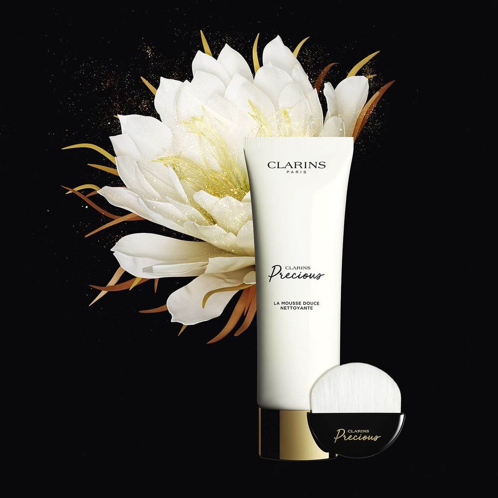 Packshot of the foaming cleanser tube and its dedicated face cleanser brush, displayed next to a shiny lotus flower